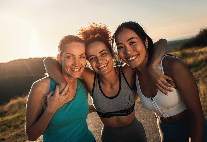 Three women smiling together outdoors